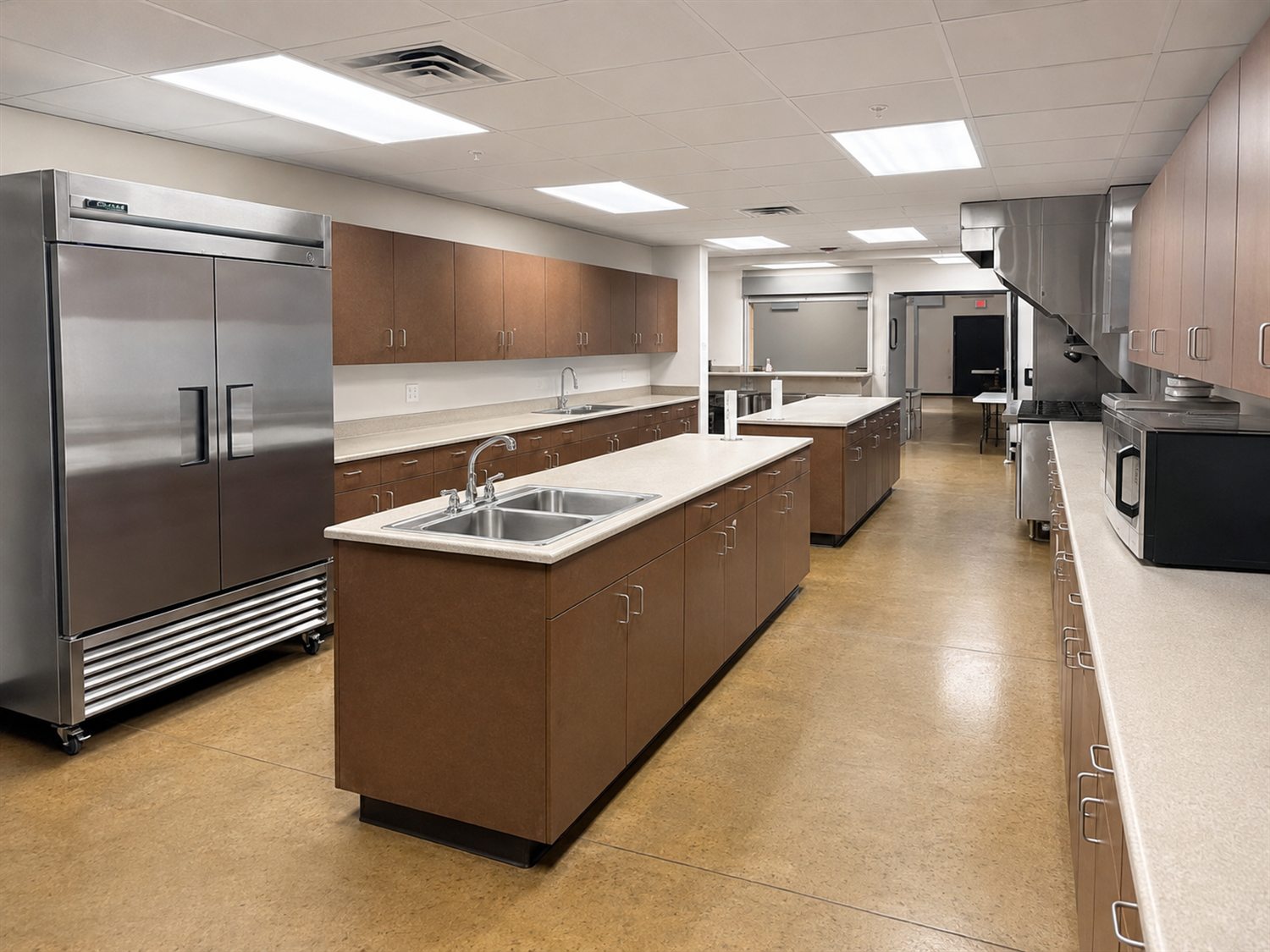 The kitchen attached to the Large Fellowship Hall, with two prep islands, commercial refrigeration, and a range under a vent hood