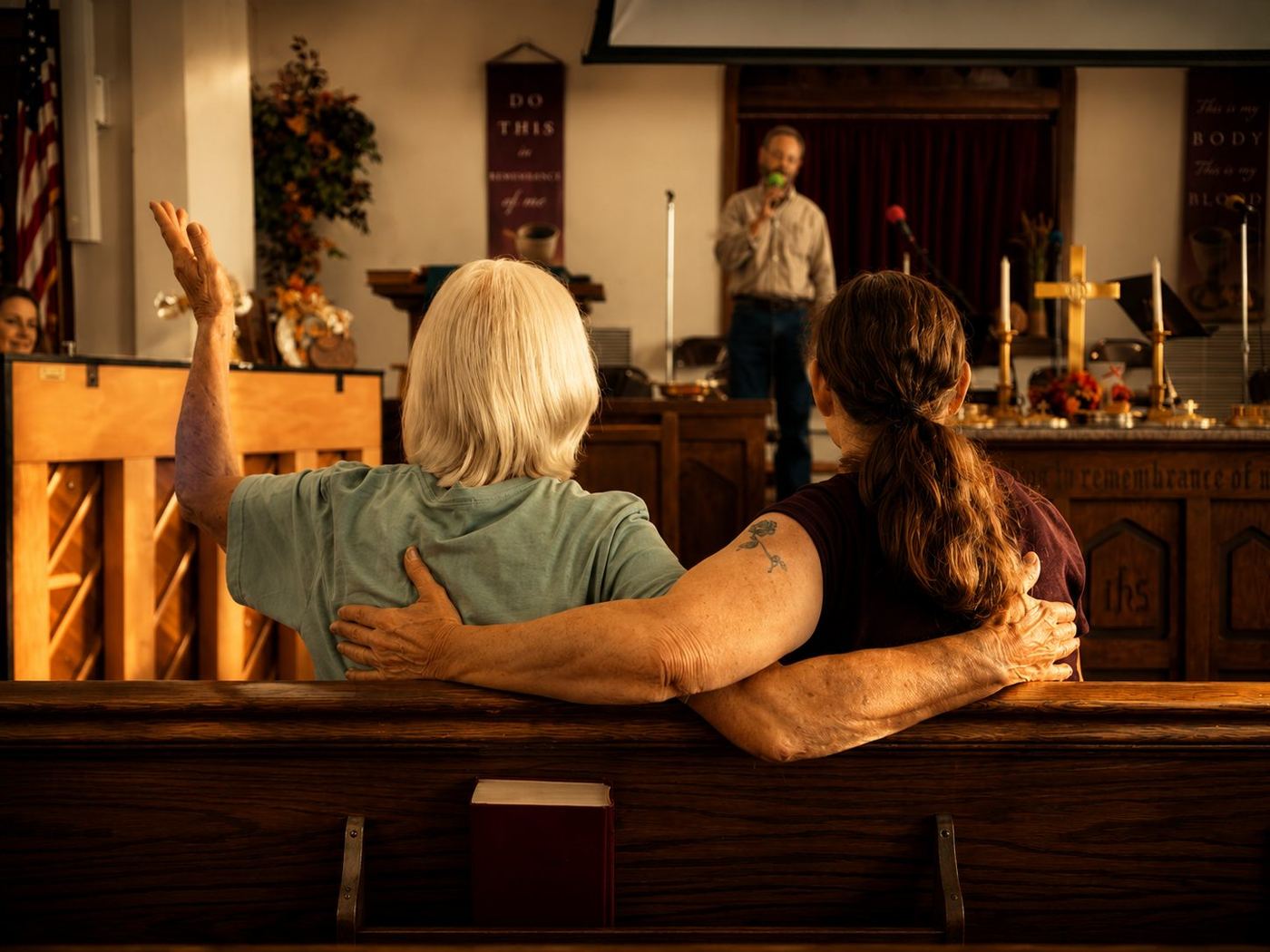 Two women linked arm in arm during worship in the sanctuary