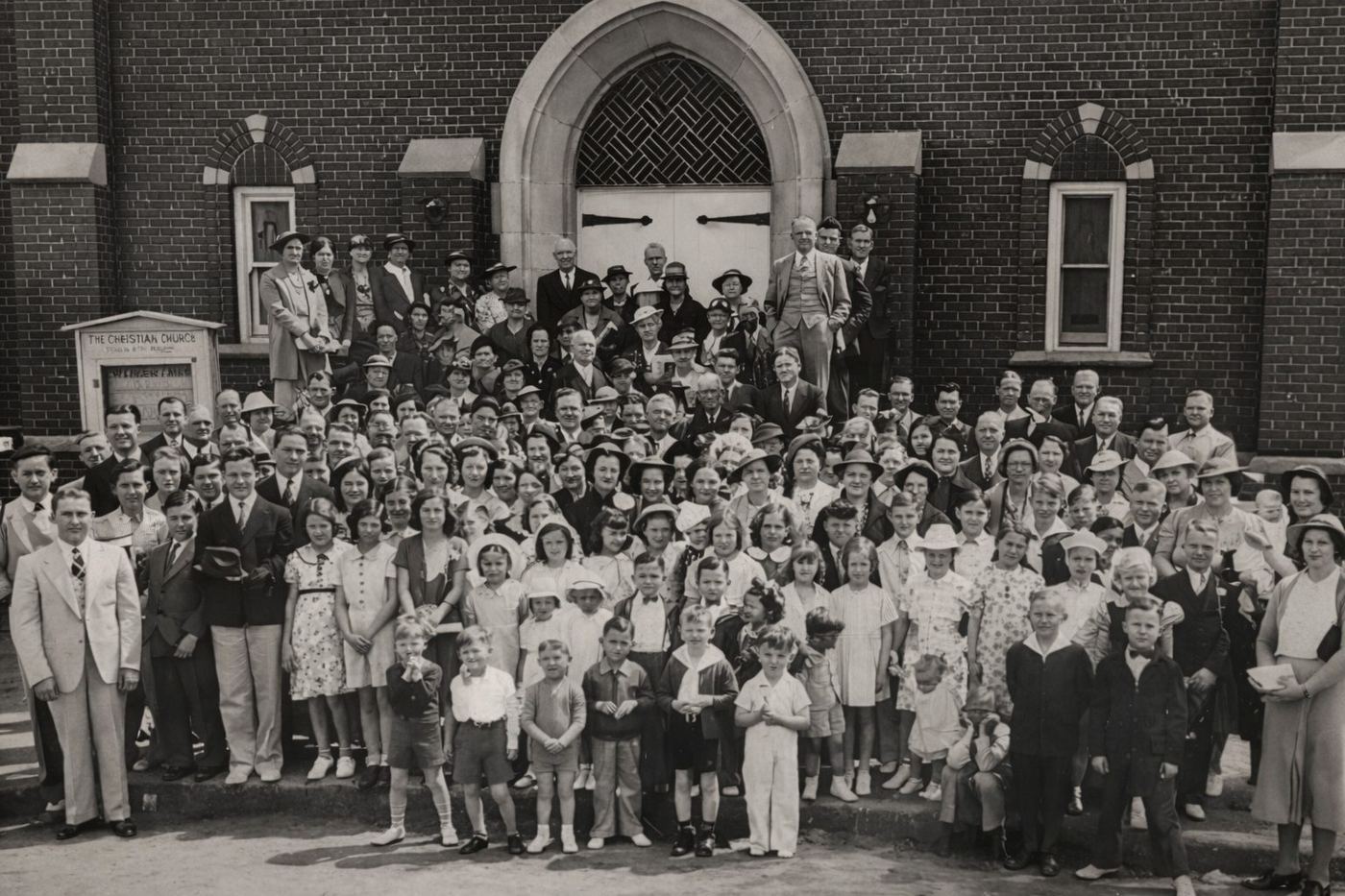 Historic black-and-white group photo of First Christian Church gathered in front of the sanctuary