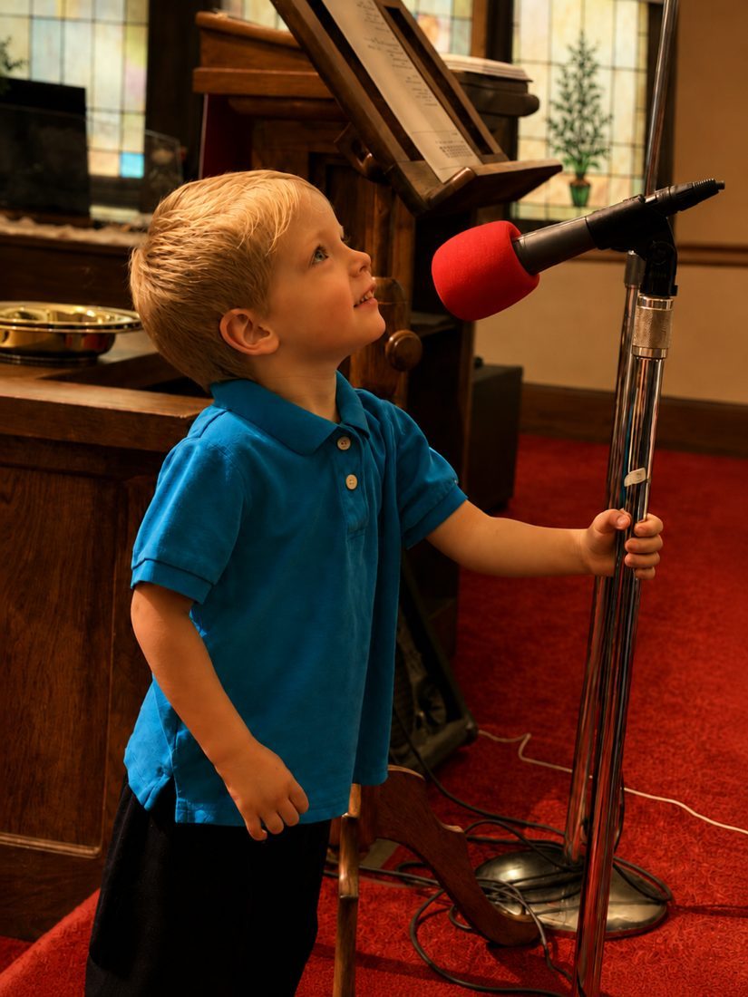 A young child participating at the microphone during worship at FCC, facing toward the right