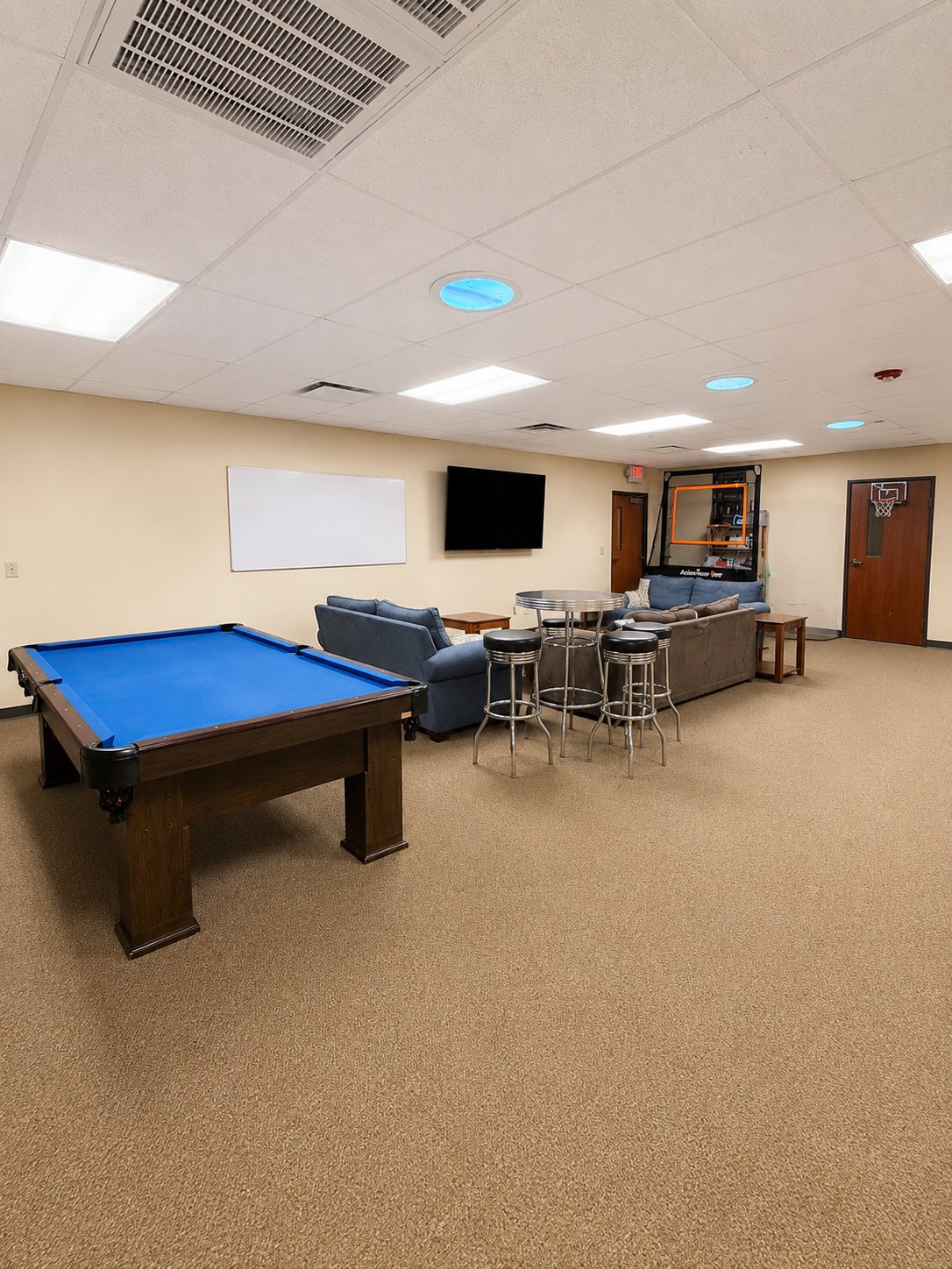 Teen room with pool table, couches, whiteboard, and television